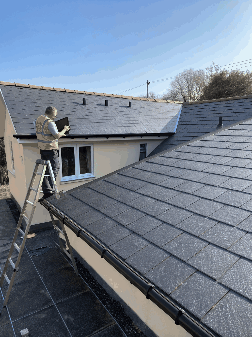 Technician on a ladder inspecting a roof edge